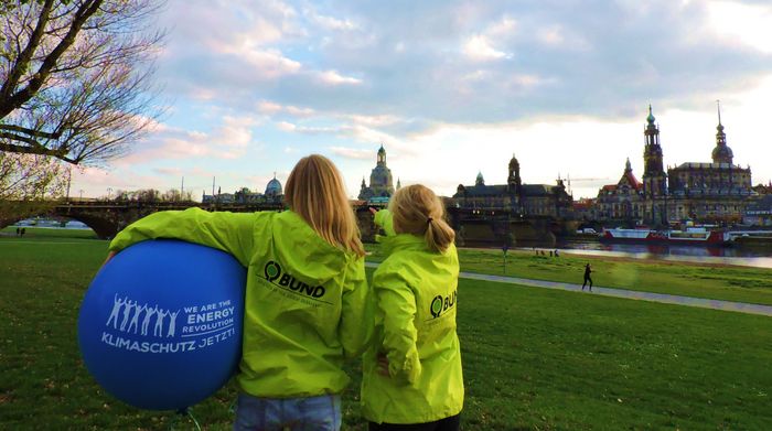 vor der Kulisse von Dresden stehen zwei Frauen mit einem Ball
