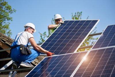 Menschen befestigen Solaranlagen auf einem Dach